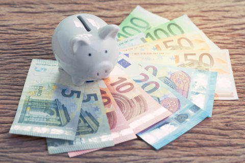 White Piggy Bank On Pile Of Euro Banknotes On Wooden Table, Fina